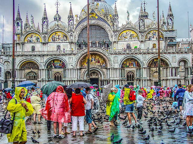 大聖堂の前に集まった、レインコートを着た観光客たち